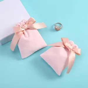 Gros plan de pochettes en velours rose avec cordons et rubans de satin sur fond bleu.