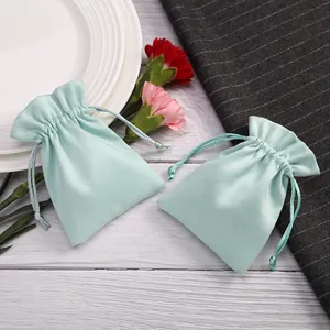 Primer plano de tela de terciopelo verde menta y cordón en pequeñas bolsas de joyas.