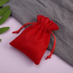 Primer plano de una bolsa de terciopelo rojo con cordón para joyas en un fondo suave