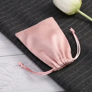 Detail eines weichen rosa Wildleder-Schmuckbeutels auf elegantem Nadelstreifen-Hintergrund