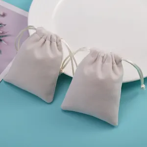 Vista detallada de dos bolsas de terciopelo beige con cordón para joyas y empaque de regalos