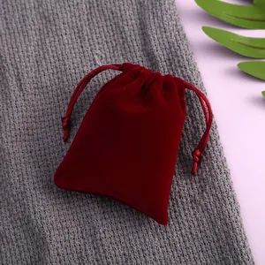 Eleganter roter Samtbeutel mit Kordelzug für Schmuck und Geschenke auf grauem Stoff.