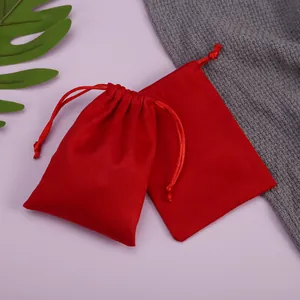 Primer plano de bolsas de terciopelo rojo con cordón para joyas en fondo púrpura