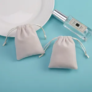 Detalle de dos bolsas de terciopelo blanco roto con cordón para empaque de joyas en fondo azul