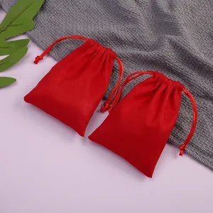 Vista detallada de dos bolsas de franela roja con cordón para guardar joyas en fondo púrpura.