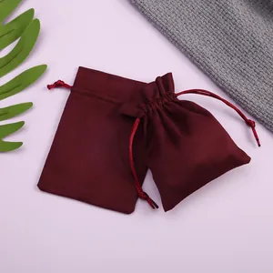 Bolsas de ante burdeos para joyas mostradas planas y cerradas sobre fondo suave