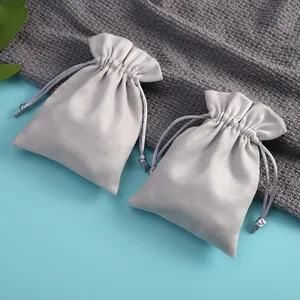 Primer plano de dos bolsas de microfibra gris claro para joyas sobre fondo azul