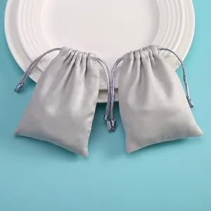 Detailed view of gray microfiber drawstring pouches for jewelry storage on a blue background