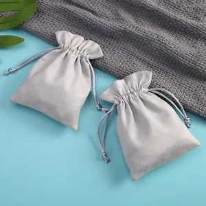 Detalle de bolsitas de terciopelo gris claro con cordón para empaque y almacenamiento de joyas