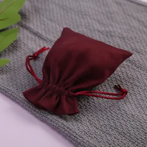 Primer plano de una bolsa de terciopelo burdeos para joyas en fondo gris texturizado