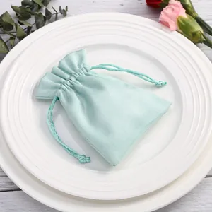 Primer plano de una suave bolsa de terciopelo verde menta con cordón en platos