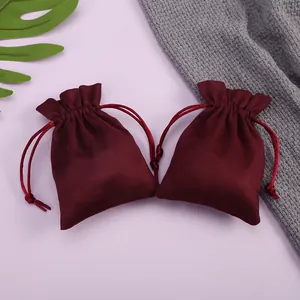 Vista detallada de dos bolsas de terciopelo granate con cordón para joyas y regalos.