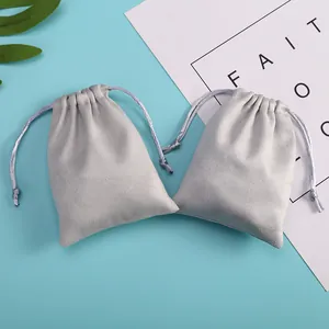 Macro view showing the soft texture of two grey velvet drawstring storage pouches.