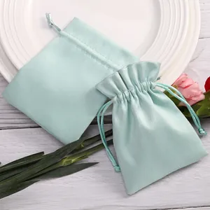 Primer plano de dos bolsas de terciopelo verde menta para joyas con cordón