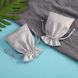 Vista de detalle de la textura suave y el cordón de dos bolsas de terciopelo gris para joyas