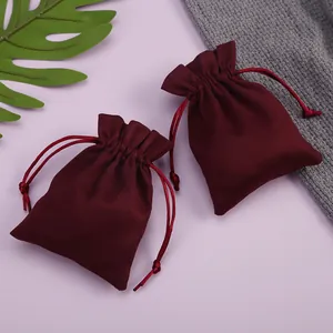 Detalle de bolsitas de terciopelo burdeos con cordón para joyas sobre fondo lila