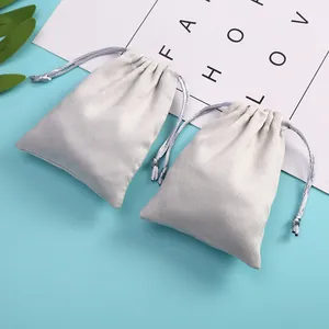 Macro view of two grey velvet drawstring jewelry pouches on a light blue background