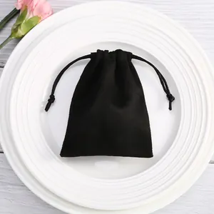 Vista detallada de una pequeña bolsa de ante negro con cordón para joyas y empaque de regalos