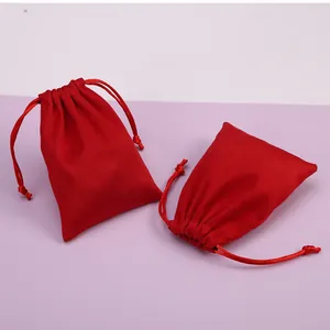 Primer plano de dos bolsas de terciopelo rojo con cordón para joyas y embalaje de regalos.