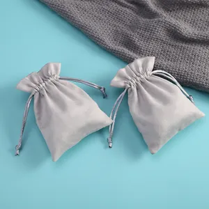 Detalle de bolsas de terciopelo gris con cordón para joyas y empaques de regalo de alta calidad