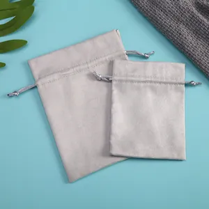 Vista detallada de dos bolsas de terciopelo gris claro con cordón para joyas