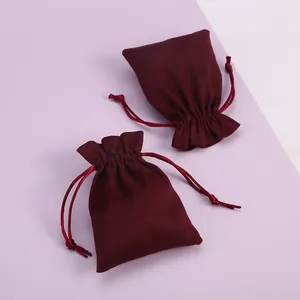 Detalle de bolsas de terciopelo rojo vino con cordón para joyas y regalos