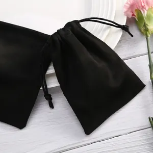 Primer plano de una pequeña bolsa de gamuza sintética negra para joyas en un plato
