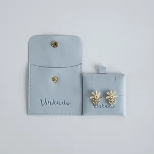 Elegant light blue suede jewelry storage pouch with snap button and pearl flower earrings