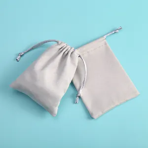 Pair of gray microfiber jewelry pouches with drawstring closure on blue background