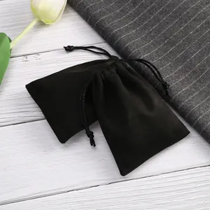 Detalle de bolsas de terciopelo negro con cordón para joyas sobre un fondo elegante.