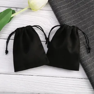 Primer plano de bolsas de terciopelo negro con cordón sobre fondo de madera blanca.