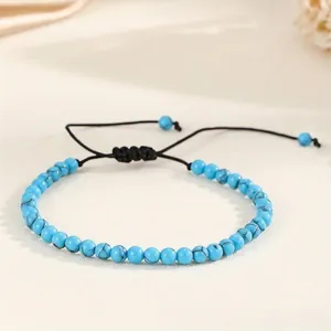 Close-up of 4mm blue stone beads on an adjustable black woven cord bracelet
