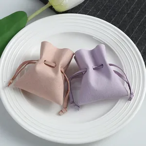 Elegant microfiber drawstring jewelry pouches in nude and lavender on a white ceramic plate
