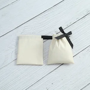 Petits pochons en coton crème pour bijoux avec nœud élégant en ruban noir satiné