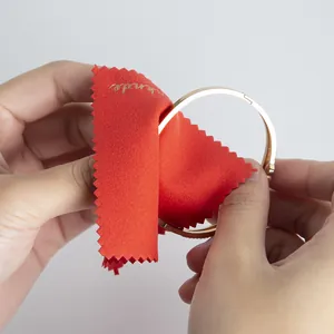 Close-up of a soft red microfiber cloth being used to polish a gold jewelry bangle.