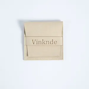 Elegante bolsa de gamuza de microfibra beige para joyas con solapa y logo de marca.