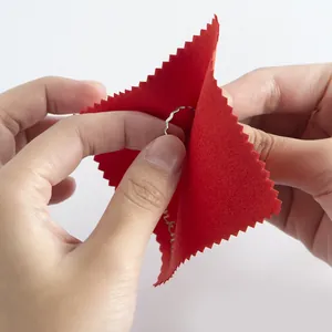 Close-up of red microfiber cleaning cloth wiping a silver ring with soft velvet texture