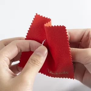 Close-up macro view of a red microfiber cleaning cloth wiping a silver wavy fashion ring