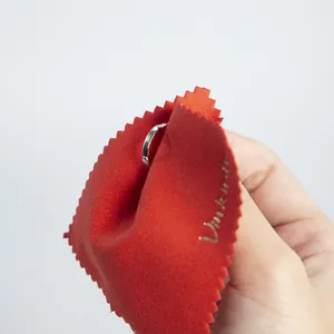 Close-up view of a red microfiber cloth used for wiping a silver ring carefully.
