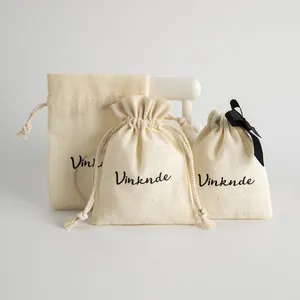Trois sacs à bijoux en lin crème avec cordon de serrage et logo noir imprimé.