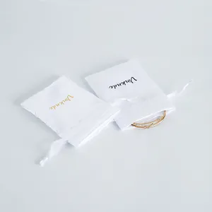 Detail view of two white satin jewelry drawstring pouches showing elegant storage utility