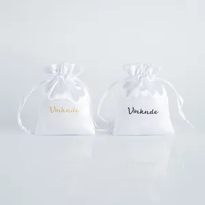Detailed macro view of white satin drawstring jewelry bags with custom logo printing