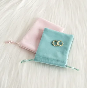 Gros plan sur des pochettes à cordon en velours rose et menthe avec boucles d'oreilles