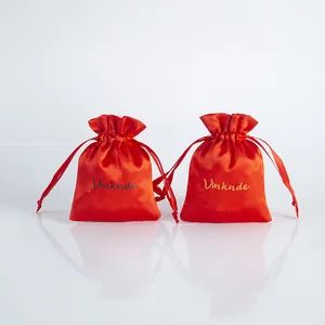 Detailed view of red satin drawstring dust bags featuring smooth silk texture and gold lettering