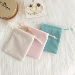 Vue rapprochée de trois pochettes à bijoux en velours pastel : crème, rose et bleu turquoise.