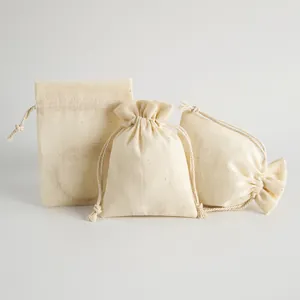 Vista detallada de tres bolsas de algodón de bambú crema con cordón para joyería