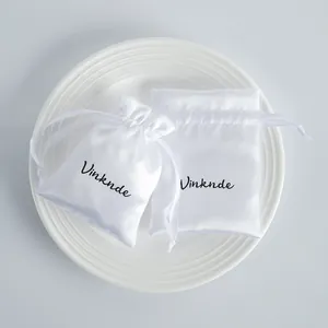 Close-up of elegant white satin drawstring jewelry pouch showing smooth fabric texture.