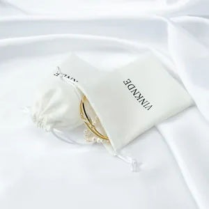 Detailed view of elegant white satin drawstring jewelry bags with VINKNDE logo