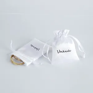 Close-up of white satin drawstring pouches for jewelry storage with brand logo