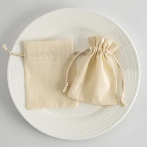 Primer plano de bolsas de algodón flameado con cordón para joyas en un plato blanco.